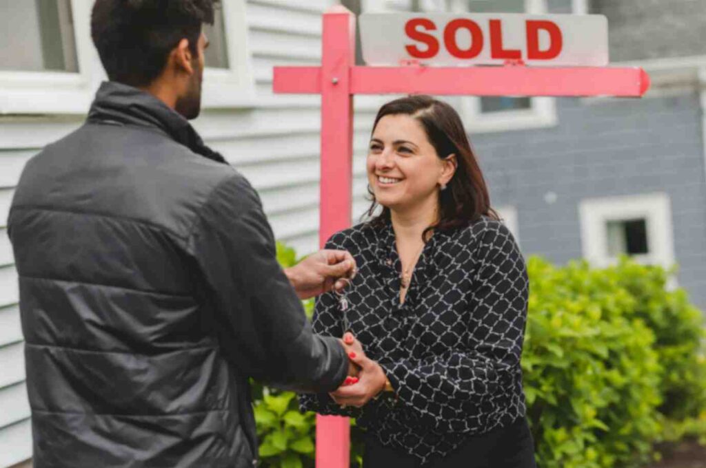 Motivated Sellers - smiley agent handing over keys to new owner